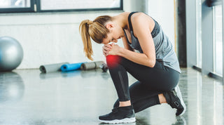 Dancer holding sore knee after twisting in sneakers on a studio floor