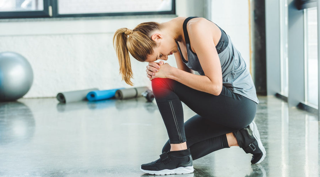 Dancer holding sore knee after twisting in sneakers on a studio floor